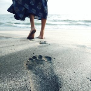 photo of woman walking barefoot on seashore